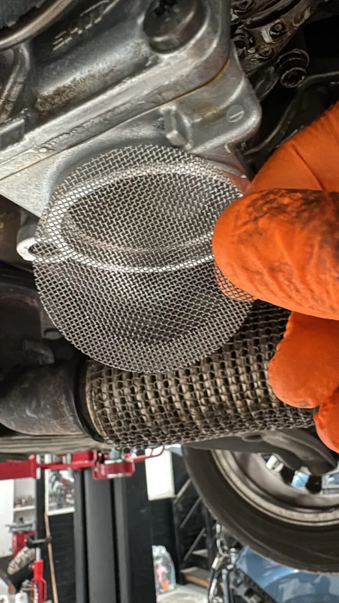 Cleaned oil pickup strainer mesh held under the car
