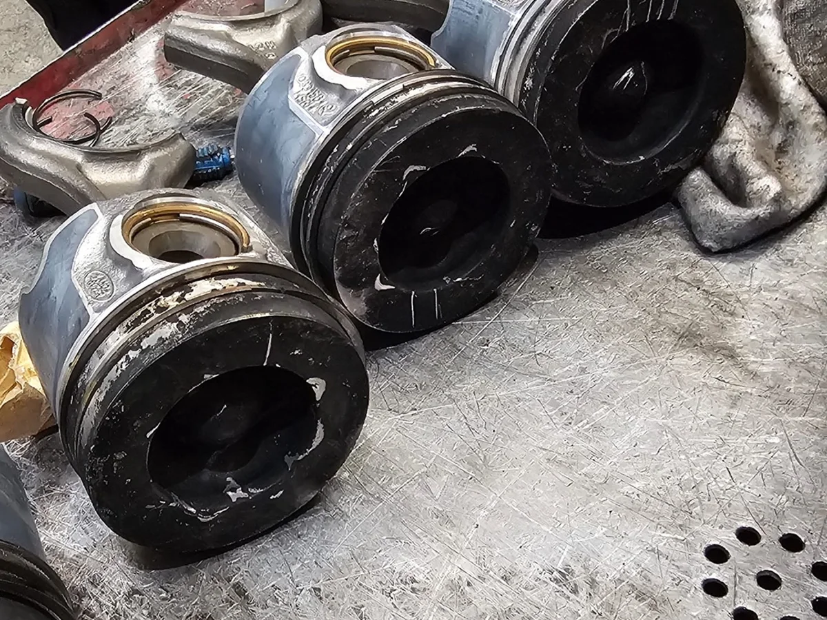 Old pistons covered in carbon, removed during an engine rebuild at our Royston workshop