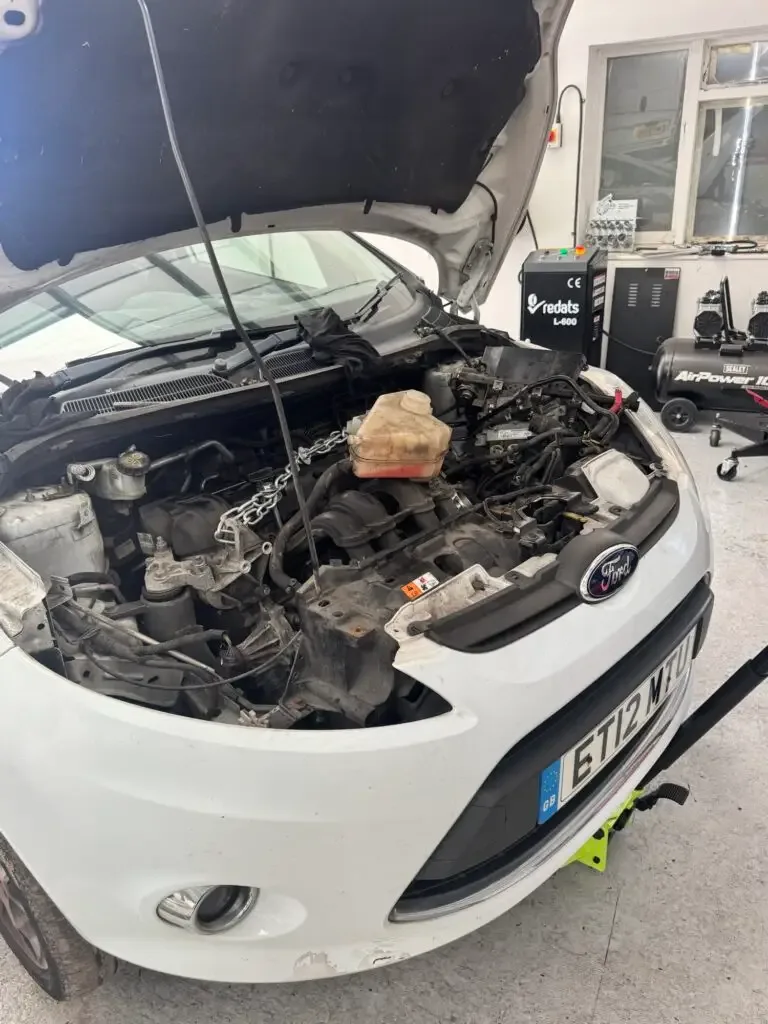 Ford Fiesta with the bonnet open, engine ready to be removed