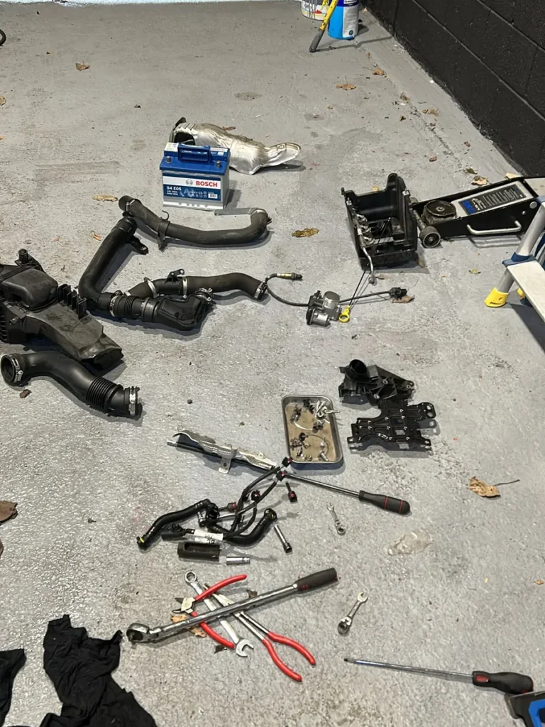 Intake pipework, air box, heat shield, battery and hand tools laid out on the floor of our Swindon workshop during a Ford Fiesta 1.0 EcoBoost wet belt replacement