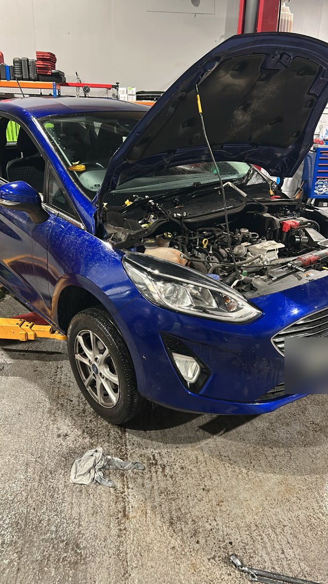 Blue Ford Fiesta 1.0 EcoBoost with the bonnet up in our Swindon workshop for a wet belt replacement