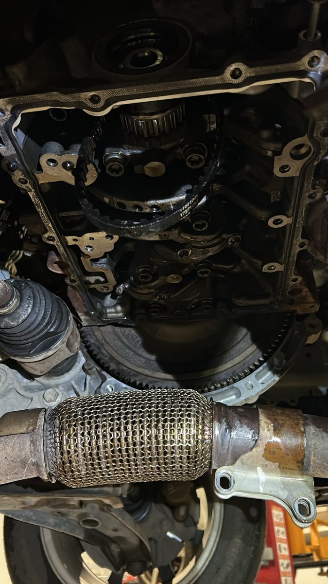 Underneath a Ford Fiesta 1.0 EcoBoost engine with the sump off, showing the oil pump belt and sprocket